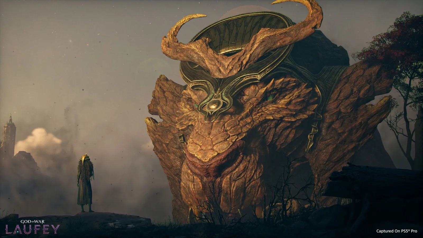 A small cloaked figure stands before a colossal horned rock creature with an ornate golden face plate in a misty dusk landscape